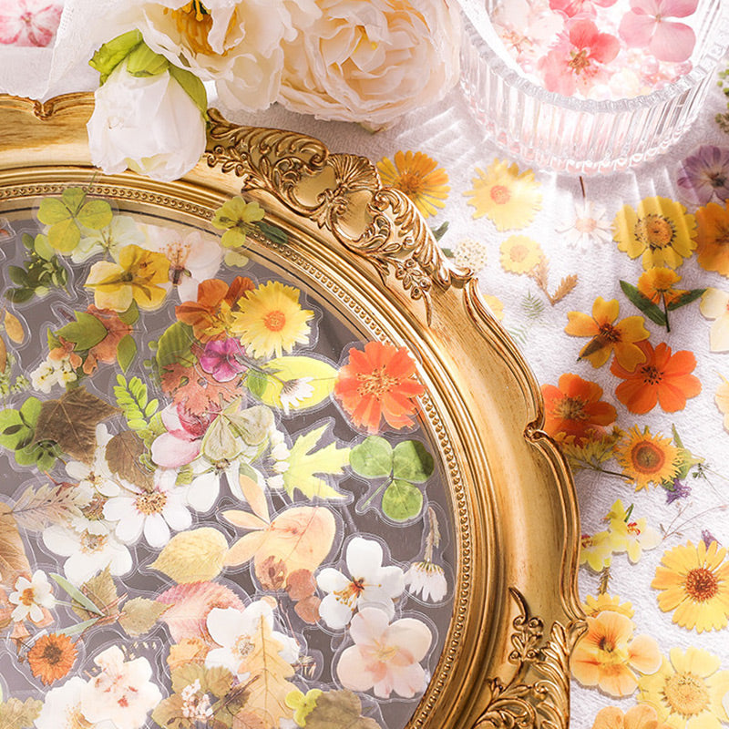 Orange, yellow and pink transparent flower stickers and leaf pieces heaped in a gold ornate frame tray