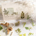 Green leaf and fern stickers on a vintage journal spread with pearls and bookmark-style cards