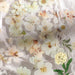 White and cream blossom stickers scattered over lace and a clear glass dish with pearl beads