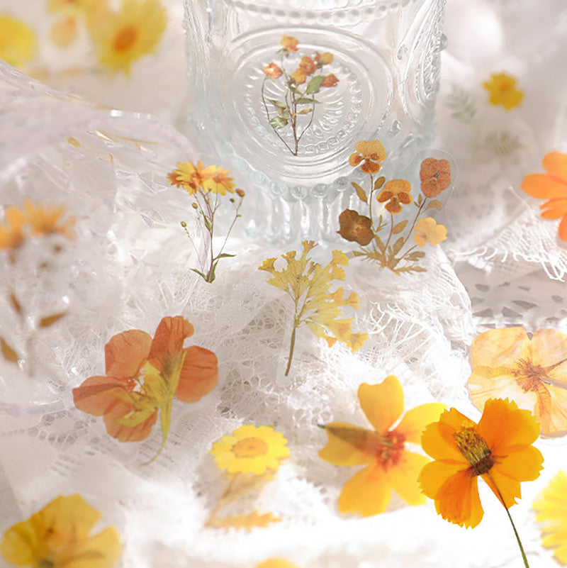 Yellow and orange flower stickers on white lace around a clear ribbed glass bottle