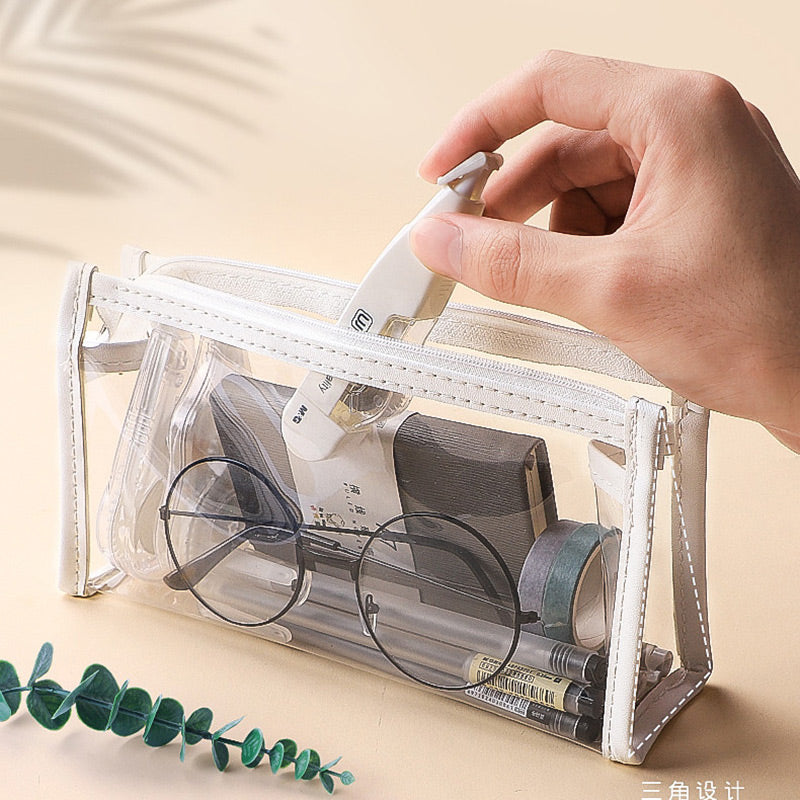 Hand placing correction tape into a clear triangular zipper pencil case with glasses inside