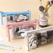 Blue, pink, and white clear triangular zipper pencil cases filled with calculators and stationery