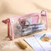 Clear triangular zipper pencil case with pink trim, filled with pens and stationery