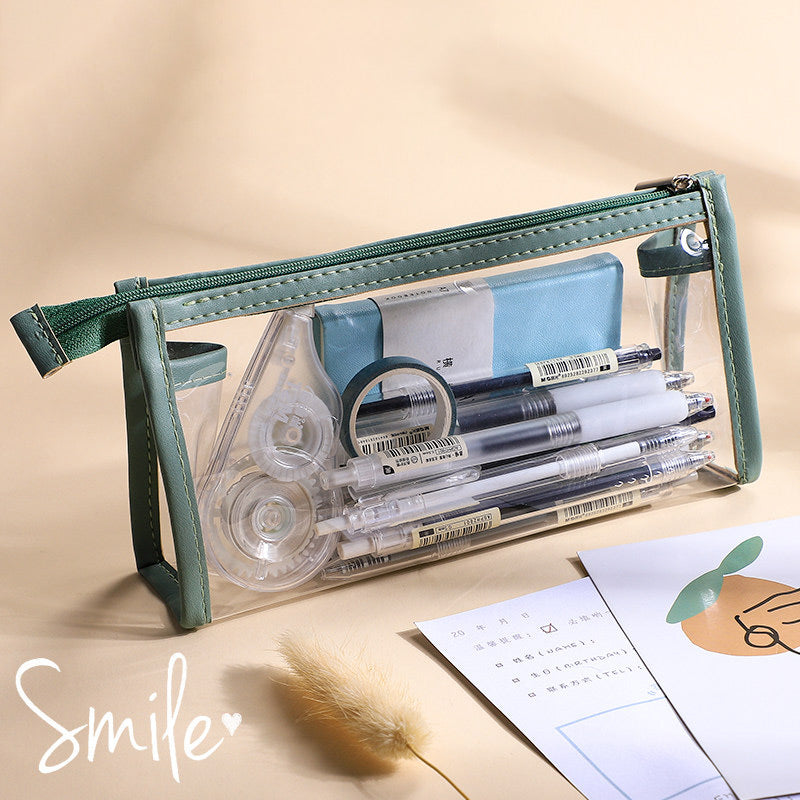 Clear triangular zipper pencil case with green trim, filled with pens and stationery