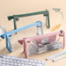 Green, blue, and pink clear triangular zipper pencil cases standing on a desk