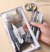 Hand placing pens and a ruler into an open clear triangular zipper pencil case