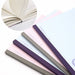 Fanned pink, blue, and grey Kokuyo Campus notebooks with inset of cream pages and dotted blue lines.
