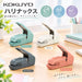 Four Harinacs stapleless staplers in teal, white, dark grey and salmon pink on a wooden desk beside notebooks