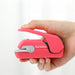Hand pressing the lever of a pink stapleless stapler to show how compact and easy to hold it is