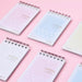 Five pastel A7 ring-bound memo pads arranged diagonally on a pink background