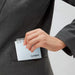 Hand slipping a light blue ring-bound memo pad into a suit pocket