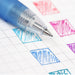 Macro shot of a gel pen nib drawing a blue swatch on grid paper