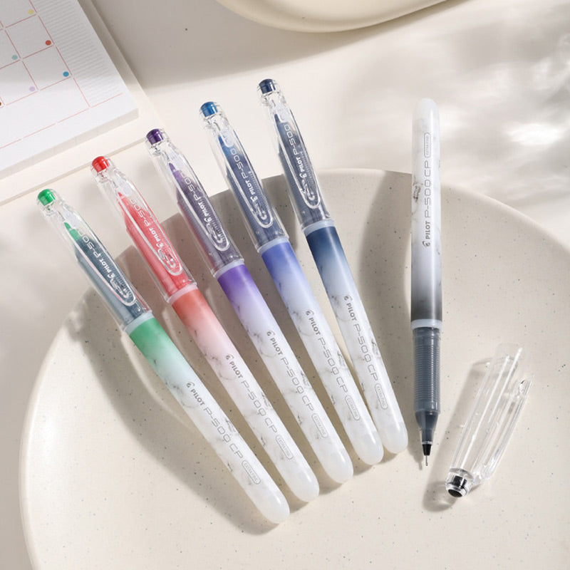 Six Pilot P-500 CP Extra Fine pens in mixed colors on a white plate, one uncapped