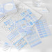 Blue index cards and pastel sticker sheets on lined notepaper with a small triangle clip on a desk