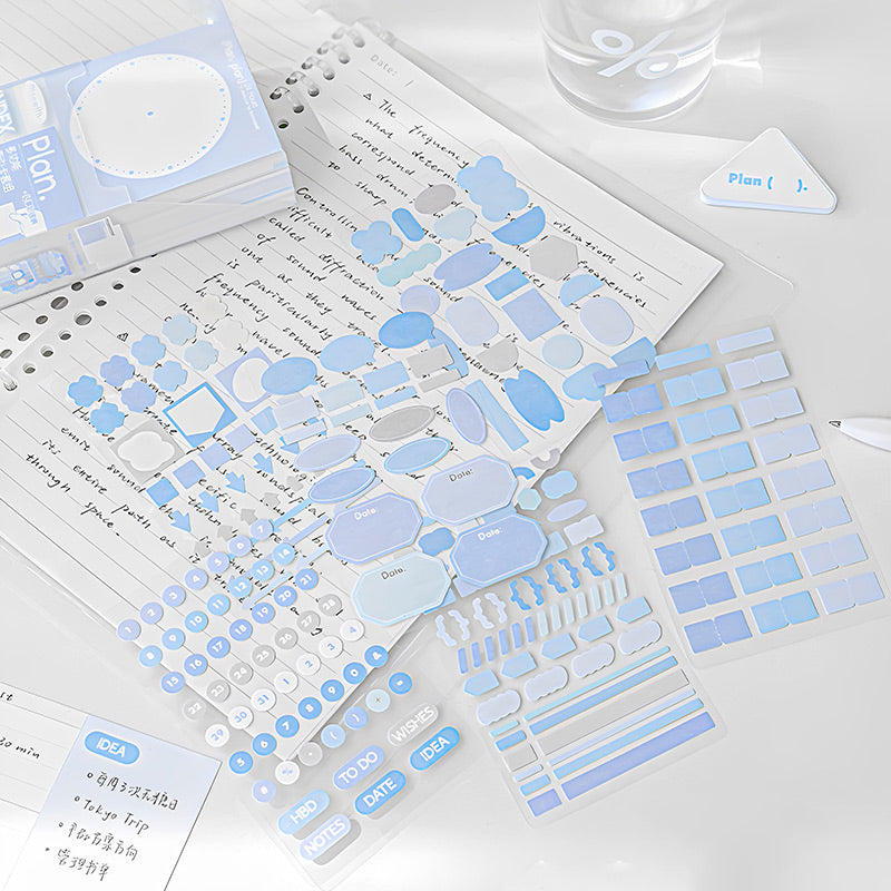 Blue index cards and pastel sticker sheets on lined notepaper with a small triangle clip on a desk