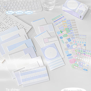 Assorted blue index cards laid out next to colourful sticker sheets and a boxed set on a study desk
