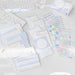 Assorted blue index cards laid out next to colourful sticker sheets and a boxed set on a study desk