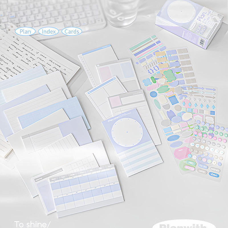 Assorted blue index cards laid out next to colourful sticker sheets and a boxed set on a study desk