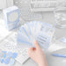 Hand fanning out blue index cards with schedule notes beside the storage box on a study desk