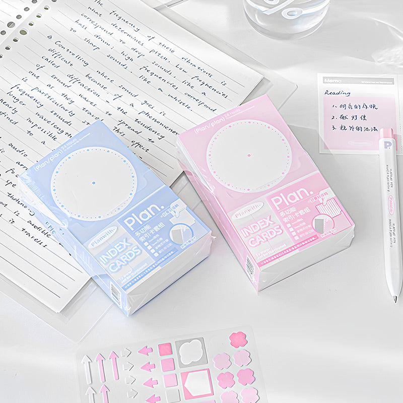 Blue and pink index card boxes beside a pink memo card, a pen and a sheet of pink stickers