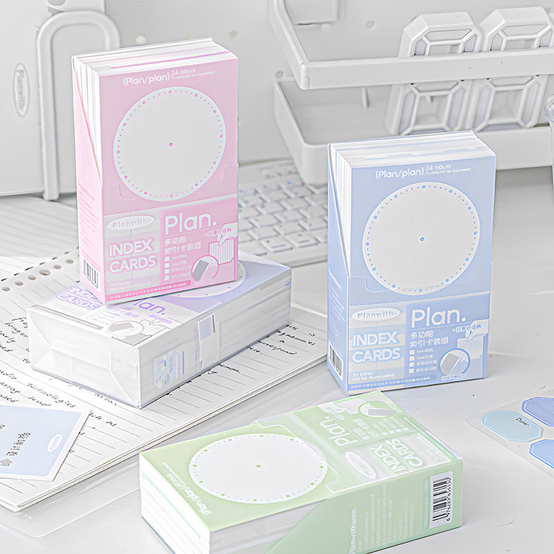 Pink, blue, green and mix index card boxes stacked and grouped on a desk with a notebook and stickers