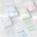 Blue, green and pink index card boxes with sticker sheets and blank planner cards scattered on a light desk
