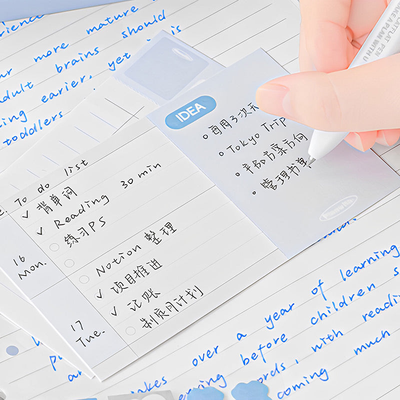Hand writing a to-do list on a blue IDEA index card placed over a lined notebook page