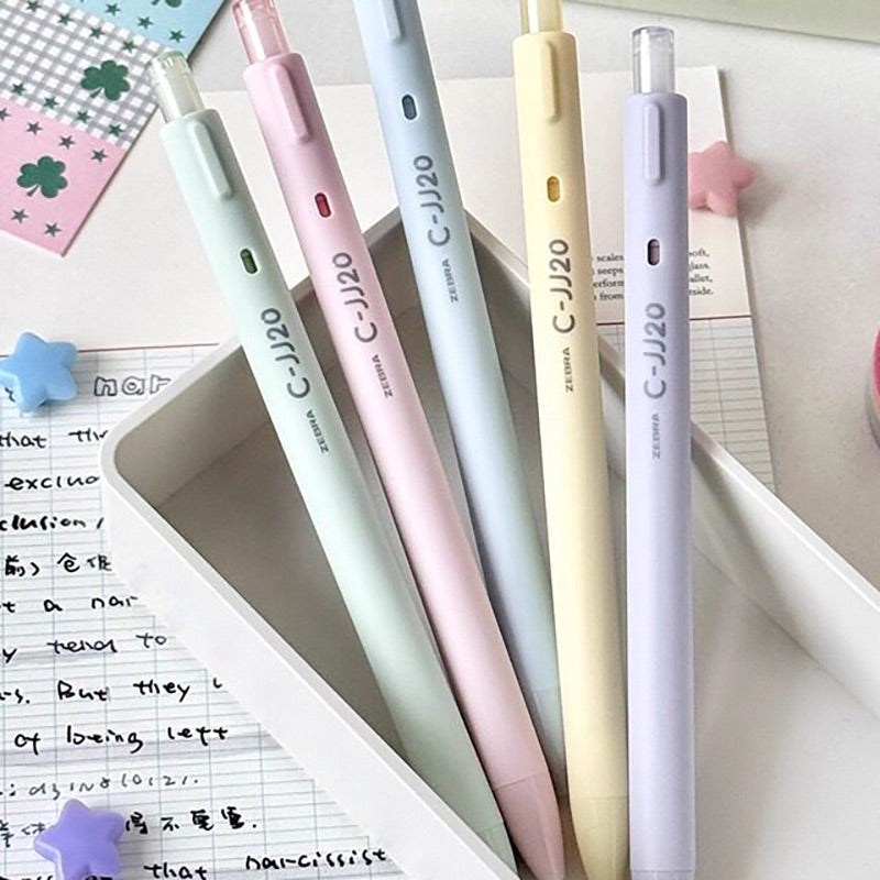 Five pastel C-JJ20 retractable gel pens standing in a white desk tray beside lined notes