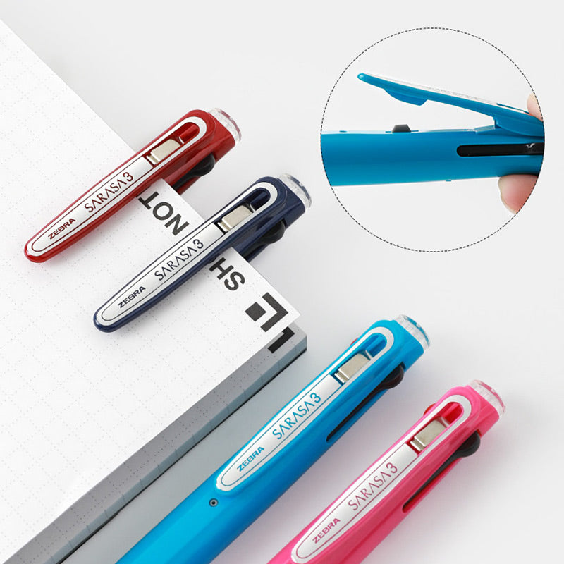 Red, navy, sky blue and pink multi pens resting on a notebook, with a close-up of the clip lifting open