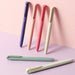 Violet, peach, coral and cream Signo RT1 pens leaning on a pink wall with sage and mint pens lying below