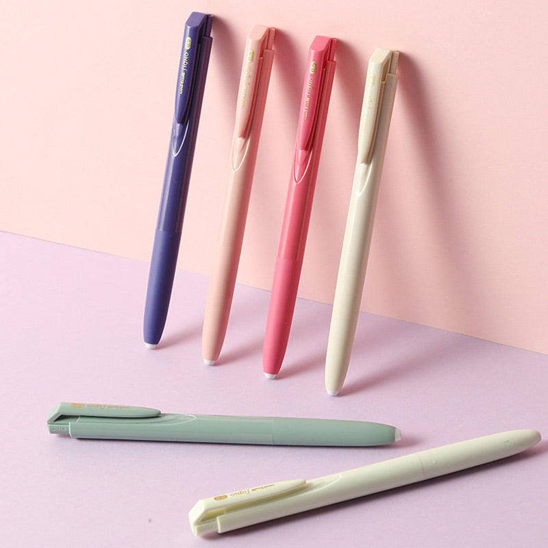 Violet, peach, coral and cream Signo RT1 pens leaning on a pink wall with sage and mint pens lying below