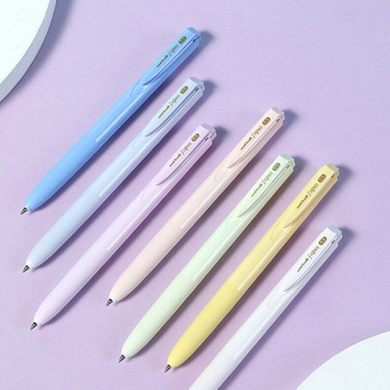 Seven pastel Signo RT1 pens in blue, periwinkle, lilac, peach, mint, yellow and white on a lilac background